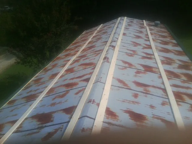 Rusted metal roof panels with new wood purlins before replacement — Storm Damage Roof Repair in Warfield by Roofing Brothers