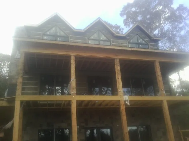 Dormers and porch framing on a large log home under construction — Roof Coating work by our crew in Warfield