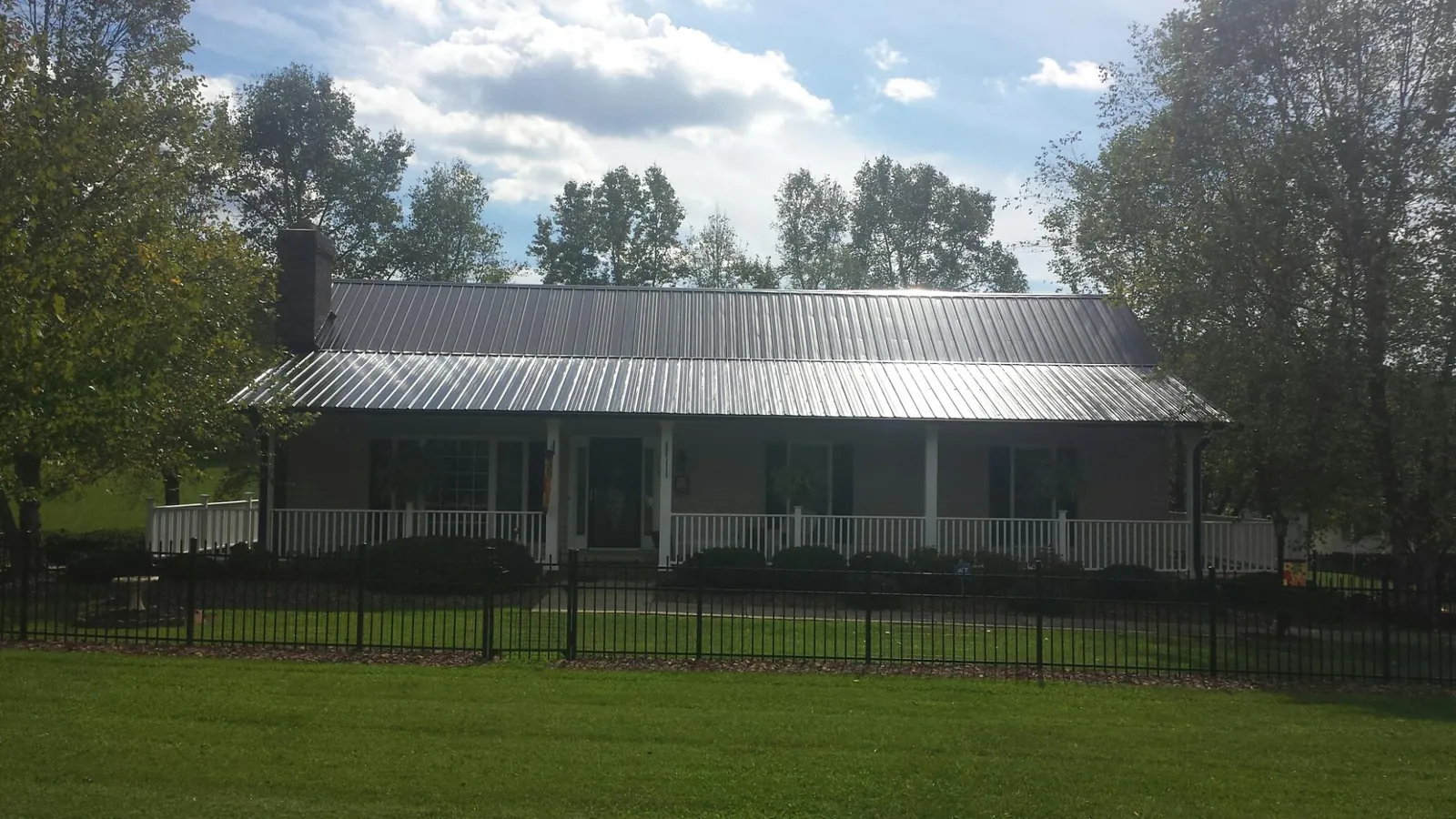 Gray metal roof on a brick ranch with a full width front porch — Gutter Guard Installation work by our crew in Warfield