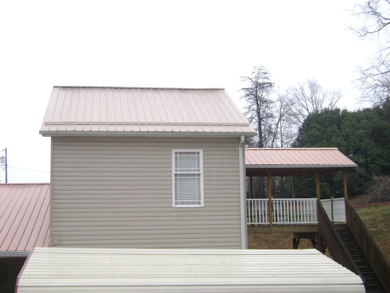 Tan metal roofs on a two story addition and attached porch, from a Roof Replacement job in Warfield