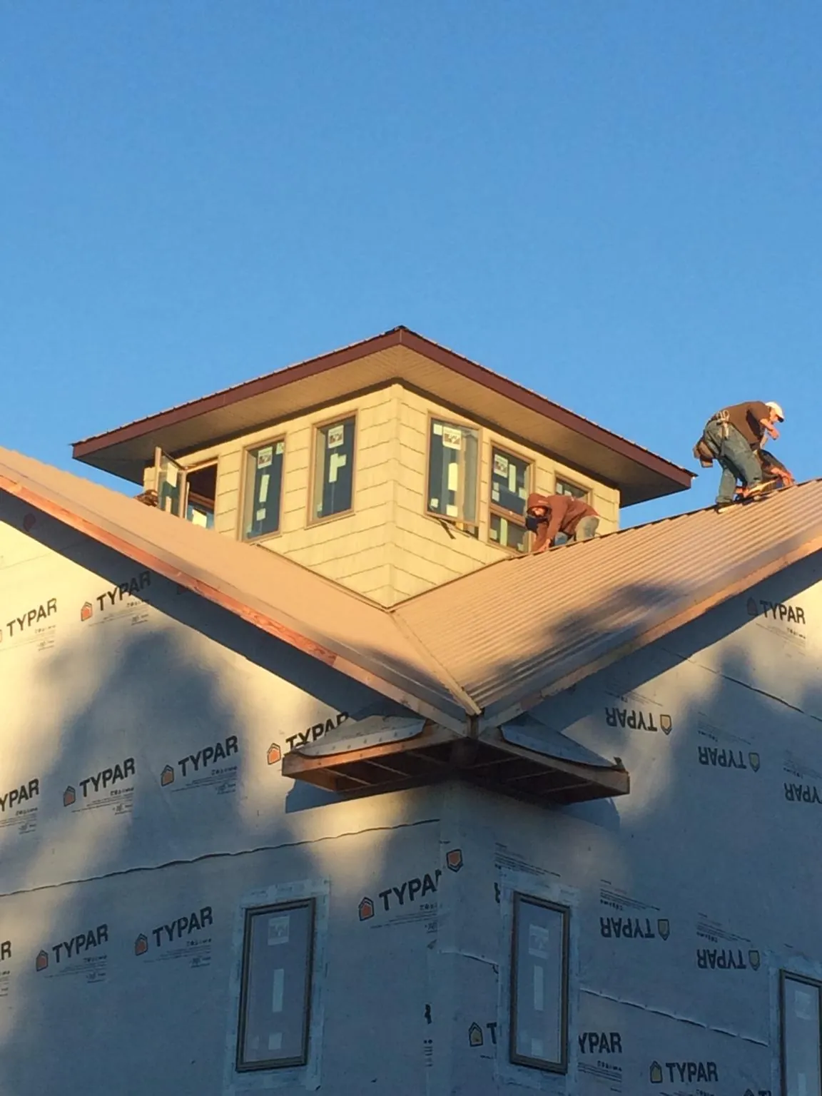 Roofers working around a rooftop cupola on a new metal roof at sunset — Roof Waterproofing in Warfield by Roofing Brothers